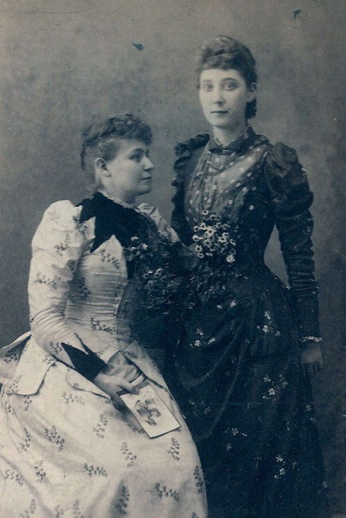 I love that the seated woman is holding a photo in her hand.  Is it an earlier picture of these two? Or friends or sisters that are absent?