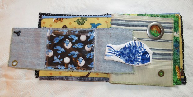 Sample page from the cloth book. The fish came from machine embroidered towel. I used some of those plastic curtain rings to make holes in one page, for peeking at animals on the next. 