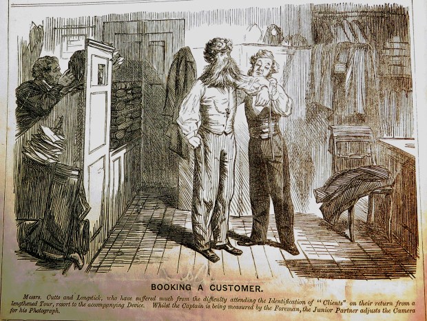 "Booking a Customer" Messrs. Cutts & Longstick, who have suffered much from the difficulty attending the Identification of "clients" on their return from a lengthened Tour, resort to the accompanying Device. Whilst the Captain is being measured by the Foreman, the Junior Partner adjusts the Camera for his Photograph.
