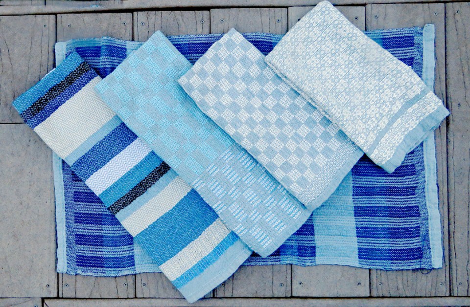 four handwoven towels laid across a fifth